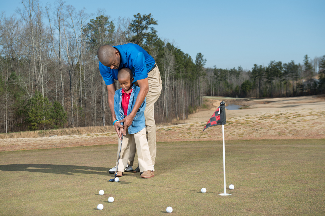 Father helps son line up a putt on the golf course