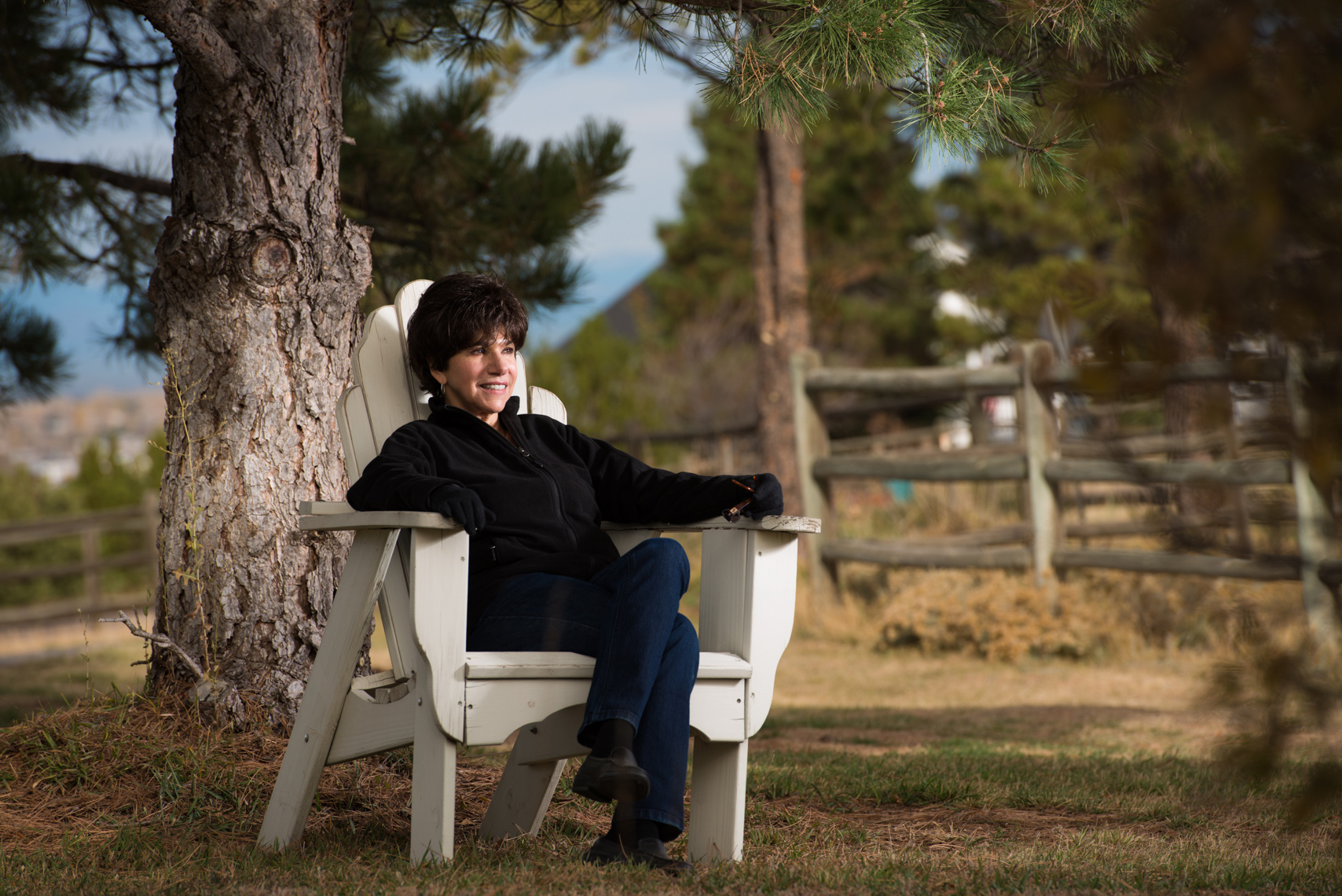 woman in adirondack chair in wooded environment in sububan Denver, Colorado